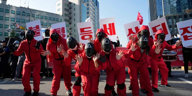 Members of the South Korean Confederation of Trade Unions wearing masks and costumes inspired by the Netflix original Korean series "Squid Game" perform during a rally demanding job security in Seoul, South Korea, Wednesday, Oct. 20, 2021. (AP Photo/Ahn Young-joon)