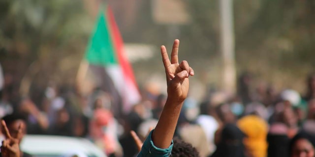 Pro-democracy protesters flash the victory sign as they take to the streets to condemn a takeover by military officials, in Khartoum, Sudan, Monday Oct. 25, 2021. Sudan’s military seized power Monday, dissolving the transitional government hours after troops arrested the acting prime minister and other officials. (AP Photo/Ashraf Idris)