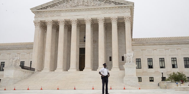 Un policier patrouille devant la Cour suprême des États-Unis à Washington, DC, le mardi 12 octobre 2021. Photographe : Emily Elconin/Bloomberg via Getty Images