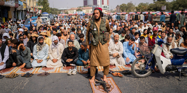 A Taliban fighter, foreground, and a group of Afghan men attend Friday prayers in Kabul, Afghanistan, Friday, Sept. 24, 2021.