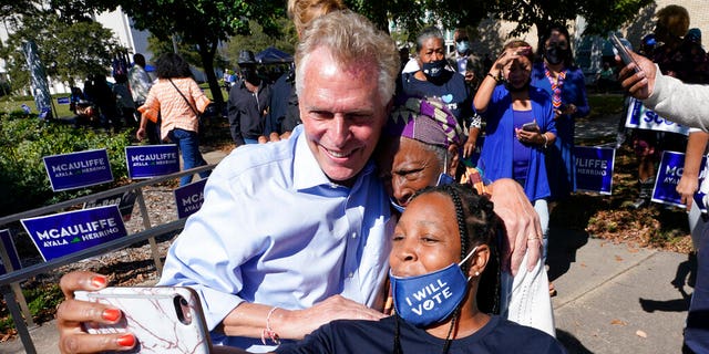 Democratic gubernatorial candidate, former Virginia Gov. Terry McAuliffe, left, poses for a photo with supporters after a rally in Norfolk, Virginia. on Oct. 17,  2021. 