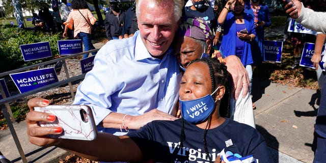 Democratic gubernatorial candidate former Virginia governor Terry McAuliffe, left, poses for a photo with supporters after a rally in Norfolk, Virginia. October 17, 2021.