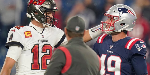 O quarterback do Tampa Bay Buccaneers, Tom Brady (12) se encontra com o long snapper do New England Patriots, Joe Cardona (49), antes de um jogo de futebol da NFL entre o New England Patriots e o Tampa Bay Buccaneers no domingo, 3 de outubro de 2021, em Foxborough, Massachusetts.