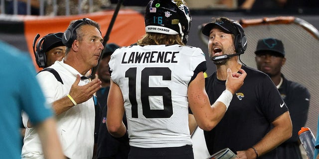 Trevor Lawrence # 16 of the Jacksonville Jaguars meets head coach Urban Meyer and coach Brian Schottenheimer in the fourth quarter against the Cincinnati Bengals at Paul Brown Stadium on September 30, 2021 in Cincinnati, Ohio.