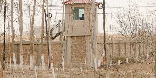 A security person watches from a guard tower around a detention facility in Yarkent County in northwestern China's Xinjiang Uyghur Autonomous Region on March 21, 2021. Four years after Beijing's brutal crackdown on largely Muslim minorities native to Xinjiang, Chinese authorities are dialing back the region's high-tech police state and stepping up tourism. But even as a sense of normality returns, fear remains, hidden but pervasive.
