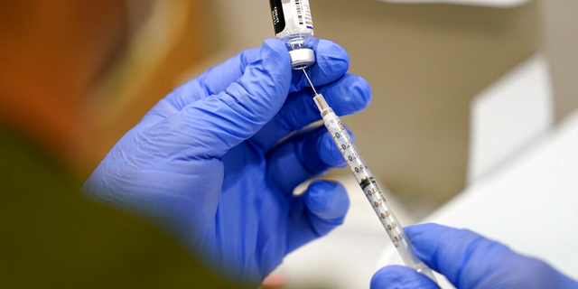 FILE - In this Oct. 5, 2021, file photo a healthcare worker fills a syringe with the Pfizer COVID-19 vaccine at Jackson Memorial Hospital in Miami. President Joe Biden’s most aggressive move yet to combat the COVID-19 pandemic is almost ready to see the light of day. The government is close to publishing the details of a new vaccination-or-testing rule covering more than 80 million Americans at companies with 100 or more workers. (AP Photo/Lynne Sladky, File) 