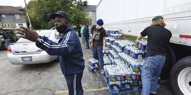 Dwayne Yarbrough leads traffic as volunteers distribute cases of bottled water to residents of God's Faith House Friday, October 15, 2021, in Benton Harbor, Michigan.  Governor Gretchen Whitmer on Thursday ordered a 