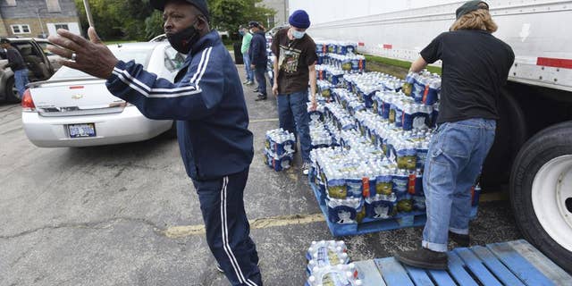 Dwayne Yarbrough leads traffic as volunteers distribute cases of bottled water to residents of God's Faith House Friday, October 15, 2021, in Benton Harbor, Michigan. Governor Gretchen Whitmer on Thursday ordered a