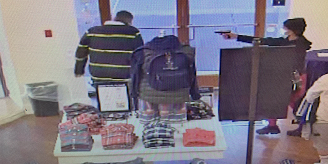 A suspect pointing a gun at an employee.