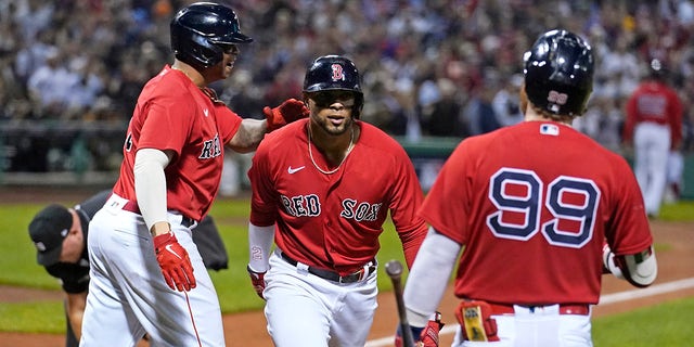 Boston Red Sox's Xander Bogaerts, center, celebrates his two-run homerun with Rafael Devers, left, and Alex Verdugo (99) in the first inning of the American League playoff baseball game against the New Yankees York at Fenway Park, Tuesday October 5, 2021, in Boston.