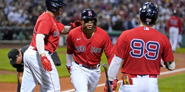 Boston Red Sox's Xander Bogaerts, center, celebrates his two-run homerun with Rafael Devers, left, and Alex Verdugo (99) in the first inning of the American League playoff baseball game against the New Yankees York at Fenway Park, Tuesday October 5, 2021, in Boston.