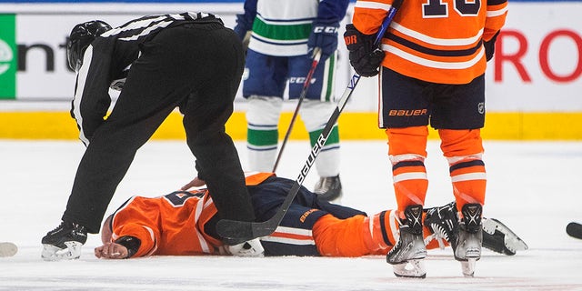 Edmonton Oilers Zack Kassian (44) lies on the ice after a fight with Vancouver Canucks Zack MacEwen (71) during a third period NHL preseason hockey game in Edmonton, Alta on Thursday, 7 October 2021.