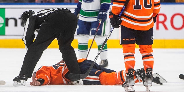 Edmonton Oilers Zack Kassian (44) lies on the ice after a fight with Vancouver Canucks Zack MacEwen (71) during a third period NHL preseason hockey game in Edmonton, Alta on Thursday, 7 October 2021.