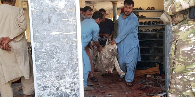 People carry the body of a victim following a bombing in Kunduz province, northern Afghanistan, Friday, Oct. 8, 2021. A powerful explosion in a mosque frequented by a Muslim religious minority in northern Afghanistan on Friday has left several casualties, witnesses and the Taliban's spokesman said. (AP Photo/Abdullah Sahil)