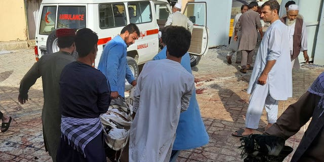 People carry the body of a bombing victim in Kunduz province, northern Afghanistan, Friday, Oct. 8, 2021. (AP Photo/Abdullah Sahil)