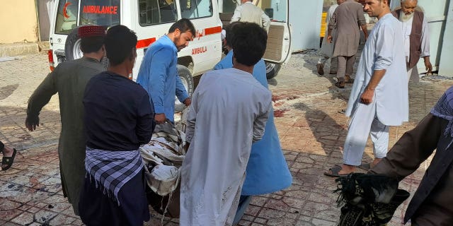 People carry the body of a bombing victim in Kunduz province, northern Afghanistan, Friday, Oct. 8, 2021. (AP Photo/Abdullah Sahil)