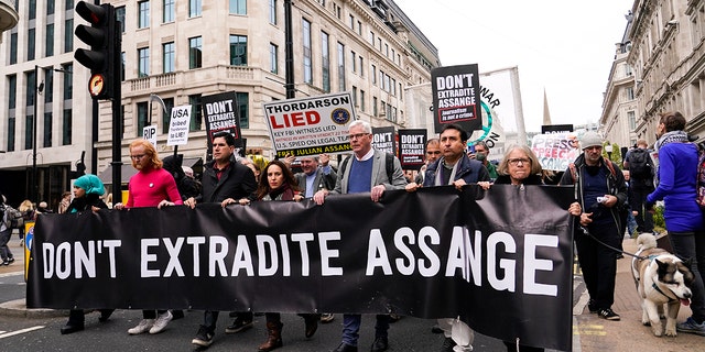 La partenaire de Julian Assange, Stella Moris, quatrième à gauche, et la rédactrice en chef de Wikileaks, Kristin Hrafnsson, cinquième à gauche, avec des partisans du fondateur de WikiLeaks, Julian Assange, tiennent des pancartes et participent à une marche à Londres, le samedi 23 octobre 2021, avant l'appel de l'affaire d'extradition de la semaine prochaine.  (AP Photo/Alberto Pezzali)