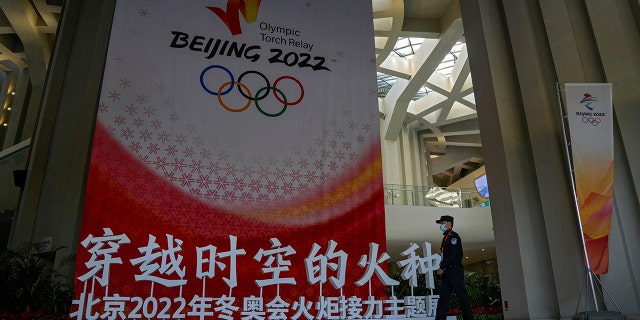 A security guard wearing a face mask to help curb the spread of the coronavirus patrols a Beijing 2022 Olympic Winter Games decoration for a welcoming ceremony for the setting for the Beijing 2022 Winter Olympic Games, which will take place is held at the Beijing Olympic Tower on Wednesday.
