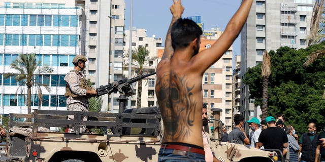 An army soldier stands on a vehicle as a supporter of the Shiite Hezbollah flashes the victory sign during armed clashes that erupted during a protest in the southern Beirut suburb of Dahiyeh, Lebanon, on Thursday.