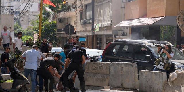 Supporters of a Shiite group allied with Hezbollah come to the aid of a comrade injured in armed clashes that erupted Thursday during a demonstration in Dahiyeh, on the southern outskirts of Beirut, Lebanon.