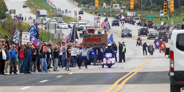 Anti-Biden demonstrators spill out into the street as they jeer the president's motorcade after a visit to the International Union of Operating Engineers Local 324 training facility in Howell, Michigan, Oct. 5, 2021.