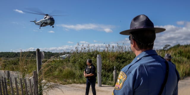 A Delaware State Trooper watches as Marine One carrying U.S. President Joe Biden takes off from Gordons Pond in Rehoboth Beach, Delaware, U.S., September 20, 2021. REUTERS/Ken Cedeno