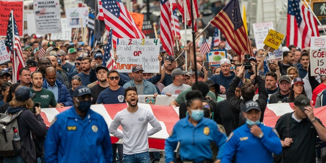 People march across the Brooklyn Bridge to protest the Covid-19 vaccine mandate for municipal workers on October 25, 2021 in New York City. All city workers, excluding uniformed correction officers, are required to have at least one dose of the COVID-19 vaccine by 5pm on October 29th. 