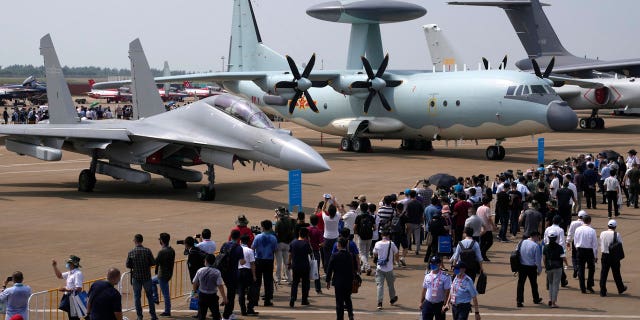 Visitors view the Chinese military's J-16D electronic warfare airplane, left, and the KJ-500 airborne early warning and control aircraft at right during 13th China International Aviation and Aerospace Exhibition, also known as Airshow China 2021, Wednesday, Sept. 29, 2021, in Zhuhai in southern China's Guangdong province. With record numbers of military flights near Taiwan over the last week, China has been stepping up its harassment of the island it claims as its own, showing an new intensity and sophistication as it asserts its territorial claims in the region. (AP Photo/Ng Han Guan)