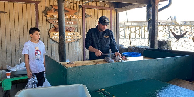 Scott Breneman, owner of West Caught Fish, slices fish for a customer at a market in Newport Beach, California on Wednesday.