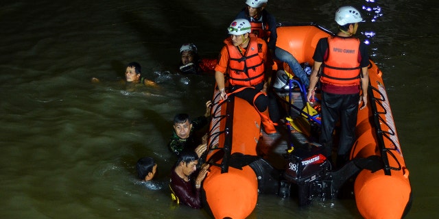 Rescuers search for victims of drowning in a river in Ciamis, West Java, Indonesia, Friday, Oct. 15, 2021. 