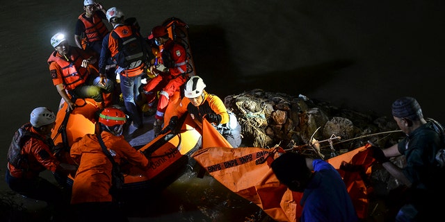 Rescuers remove a body from the water during a search for the victims of drowning in a river in Ciamis, West Java, Indonesia, Friday, Oct. 15, 2021. 