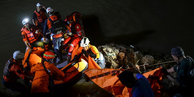 Rescuers remove a body from the water during a search for the victims of drowning in a river in Ciamis, West Java, Indonesia, Friday, Oct. 15, 2021. 