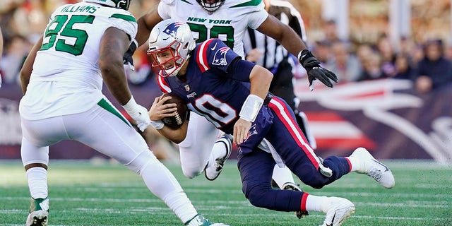 New England Patriots quarterback Mac Jones (10) tries to thread between New York Jets Quinnen Williams (95) and Sheldon Rankins, rear, during the second half of a game, Sunday, Oct. 24, 2021, in Foxborough, Mass. 