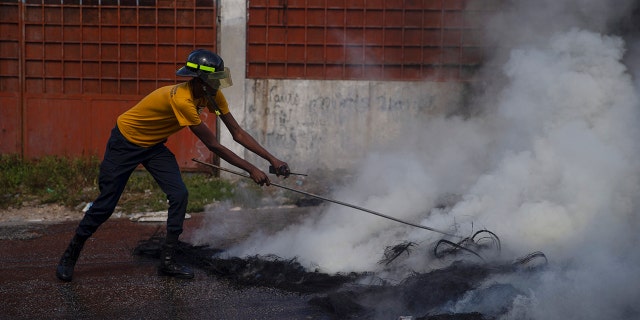 A firefighter puts out a smoldering road block set by protesters in Port-au-Prince, Haiti, on Monday. 