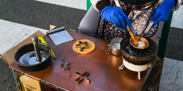 In this 2019 photo, a street vendor prepares dalgona (also known as ppopgi) candy in Busan, South Korea.  This old-fashioned candy is loved by nostalgic South Koreans.