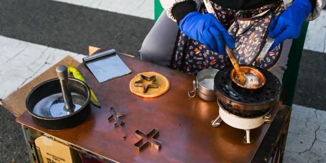 In this 2019 photo, a street vendor prepares dalgona (also known as ppopgi) candy in Busan, South Korea.  This old-fashioned candy is loved by nostalgic South Koreans.