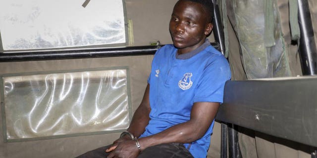 Murder suspect Masten Wanjala sits in the back of a police truck after being taken by police to a scene to identify the location of alleged victim remains, on the outskirts of Nairobi, Kenya Wednesday, July 14, 2021. Police in Kenya said Friday, Oct. 15, 2021 that the man who police say confessed to killing a dozen children and escaped from detention this week has been killed by a mob near his home in Bungoma county. (AP Photo)