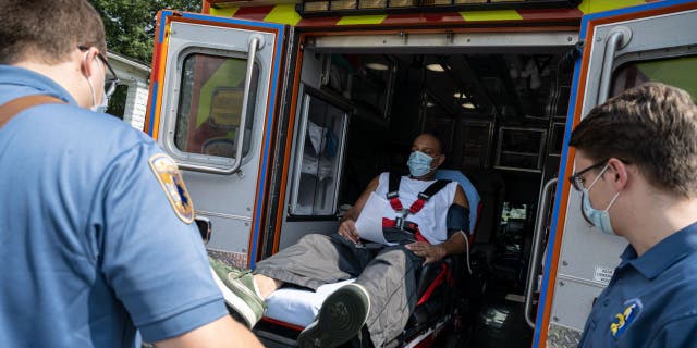 Members of Louisville Metro Emergency Medical Services load a patient experiencing a suspected COVID-19 emergency into an ambulance outside the patient's home on Sept. 13, 2021 in Louisville, Kentucky. (Photo by Jon Cherry/Getty Images)