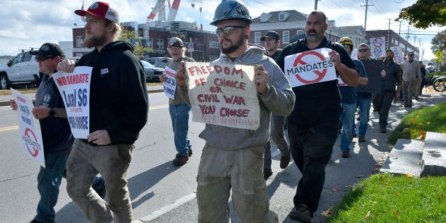 Justin Paetow, center, a tin shop worker at Bath Iron Works, takes part in a demonstration against COVID-19 vaccine mandate outside the shipyard on Friday, Oct. 22, 2021, in Bath, Maine. (AP Photo/Josh Reynolds)