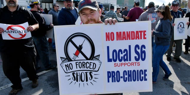 Alec Young, a shipfitter at Bath Iron Works, center, demonstrates against COVID-19 vaccine mandates outside the shipyard on Friday, Oct. 22, 2021, in Bath, Maine. (AP Photo/Josh Reynolds)