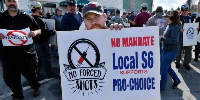 Alec Young, a shipfitter at Bath Iron Works, center, demonstrates against COVID-19 vaccine mandates outside the shipyard on Friday, Oct. 22, 2021, in Bath, Maine. (AP Photo/Josh Reynolds)