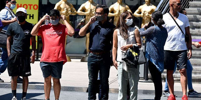 People wearing masks wait to cross the street in Hollywood, 캘리포니아.