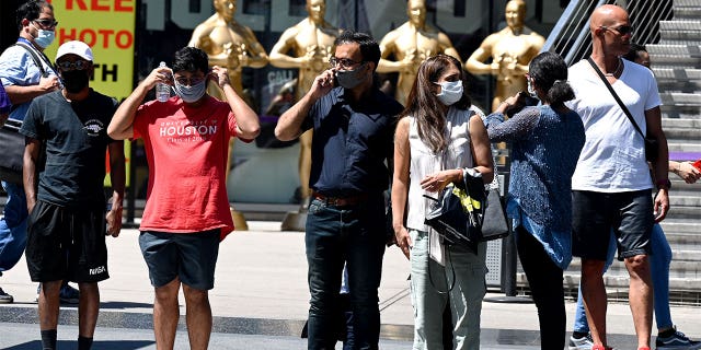 People wearing masks wait to cross the street in Hollywood, California.