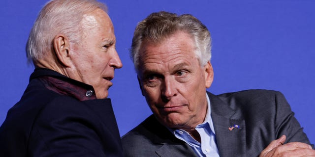 President Biden and Democratic candidate for governor of Virginia Terry McAuliffe interact onstage at a rally in Arlington, Virginia, Oct. 26, 2021.