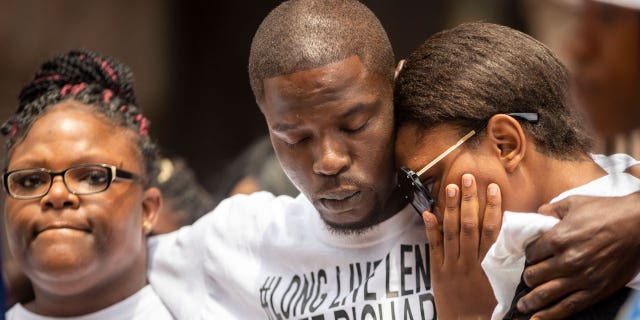 In the July 9, 2021 file photo, from left, Cheryl Frazier, sister of Leneal Frazier; Orlando Frazier, brother of Leneal; and Jamie Bradford,, daughter of Leneal, embrace one another during a news conference outside of City Hall in Minneapolis. Leneal Frazier was killed earlier in the week after his vehicle was struck by a squad car that police said was pursuing another driver linked to several robberies. Frazier was not involved in the pursuit. A Minneapolis police officer has been charged with manslaughter and vehicular homicide in a fatal crash in July that occurred while the officer was pursuing a stolen vehicle, a prosecutor announced Friday, Oct. 22. (Antranik Tavitian/Star Tribune via AP File)