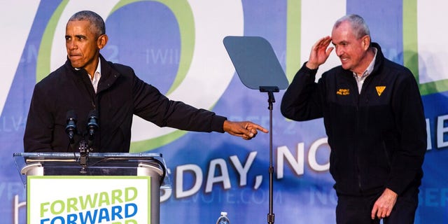 Former President Barack Obama points toward Gov. Phil Murphy, who salutes him on stage, during an early vote rally at Weequahic Park, Saturday, Oct. 23, 2021, in Newark, N.J. (AP Photo/Stefan Jeremiah)