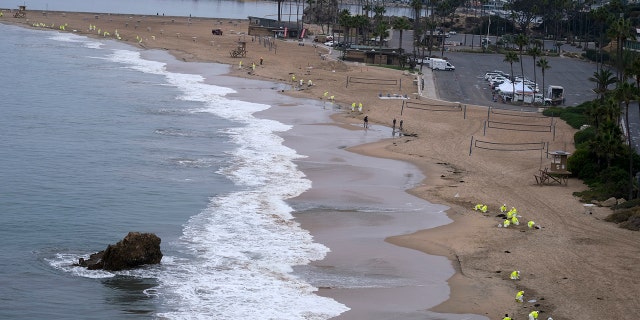 Workers in protective suits clean the contaminated beach in Corona Del Mar after an oil spill in Newport Beach, 캘리포니아, 10 월. 7, 2021.