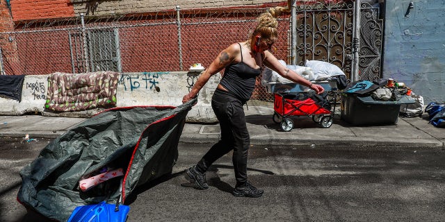 SAN FRANCISCO, CA - MAY 6: Homeless woman Tara Lowe hauls her belongings after street cleaning came through to clean Willow Street in the Tenderloin on Wednesday, May 6, 2020 in San Francisco, California.