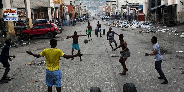 Youths play soccer next to businesses that are closed due to a general strike in Port-au-Prince, Haiti, on Monday.