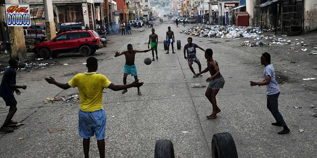 Youths play soccer next to businesses that are closed due to a general strike in Port-au-Prince, Haiti, on Monday.